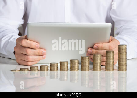 Businessman Using Digital Tablet Laughing At Desk Banque D'Images