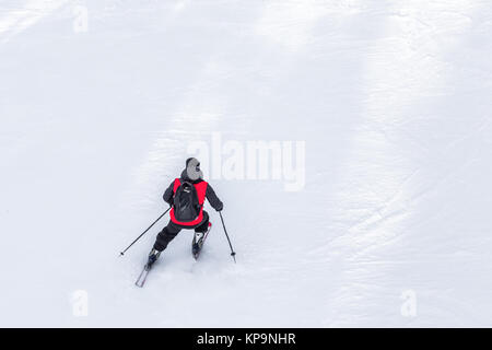 Skieur homme avec manteau rouge et noir sac à dos ski sur la neige fraîche et blanche sur la pente de ski sur d'hiver ensoleillée journée avec copie espace dans la montagne d'Uludag Bursa, Turquie Banque D'Images