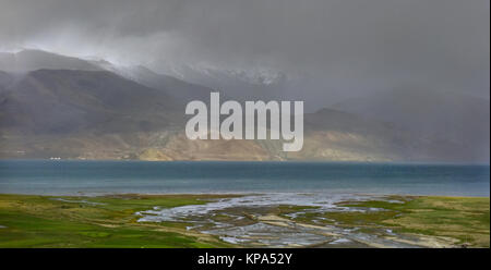 Soir le brouillard sur les hautes montagnes du lac : nuages gris descendent jusqu'à la montagne, les cacher, les derniers rayons de soleil illuminent les eaux du Banque D'Images
