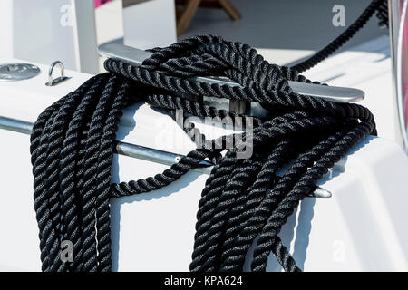 Close-up d'une corde d'amarrage avec une extrémité nouée autour d'un crochet attaché sur une jetée en bois. Amarre nautique Banque D'Images