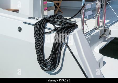 Close-up d'une corde d'amarrage avec une extrémité nouée autour d'un crochet attaché sur une jetée en bois. Amarre nautique Banque D'Images