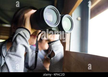 Femme Asiatique de l'utilisation des jumelles à maison en bois Banque D'Images