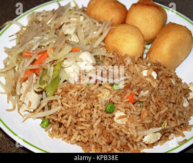 Prendre de la nourriture chinoise sur une assiette. Boules de poulet frit, poulet chop suey et riz frit au poulet avec légumes Banque D'Images