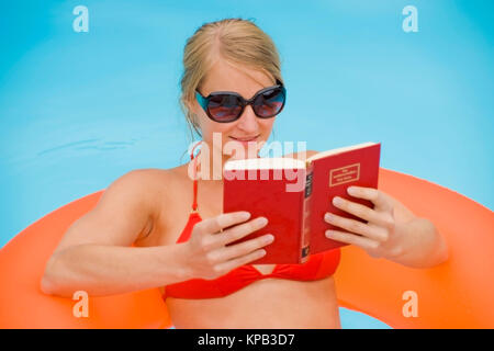 Communiqué de modèle, Junge Frau beim Lesen im piscine d'- Woman Reading in swimming pool Banque D'Images