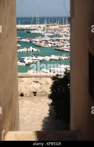 Vue sur la mer bleue avec des bateaux entre deux murs, en Italie. Banque D'Images