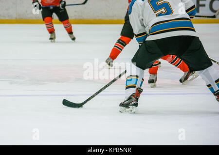 Libre de droit de joueurs de hockey' jambes et pieds en rouge et noir sur la glace patinage uniforme Banque D'Images