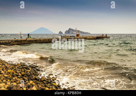 Côte rocheuse de la jetée d'embarquement l'île de Panarea et dans l'arrière-plan le volcan Stromboli et deux rochers émergeant de la Mer Tyrrhénienne Banque D'Images