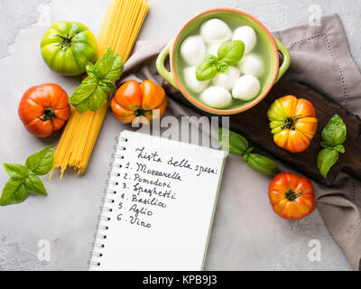 Les pâtes, tomate, mozzarella still life sur fond rustique gris. Les produits traditionnels et les liste d'achats de nourriture pour les spaghettis à la tomate en italien Banque D'Images