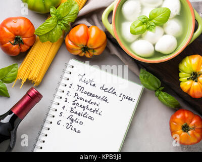 Les pâtes, tomate, mozzarella still life sur fond rustique gris. Les produits traditionnels et les liste d'achats de nourriture pour les spaghettis à la tomate en italien Banque D'Images