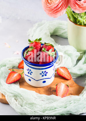 Une fraise mûre en émail mug sur planche de bois avec le textile. Printemps Été collation santé aux fruits Banque D'Images