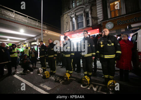 Les pompiers de rendre hommage comme les gens prennent part à une marche silencieuse pour marquer les six mois anniversaire de l'incendie de la tour de Grenfell, dans l'ouest de Londres. Banque D'Images