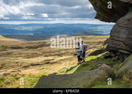 Les marcheurs près de Edale Rocks en observant le paysage de lande et de la vue panoramique sur la campagne, Kinder Scout, Derbyshire Peak District, England, UK Banque D'Images