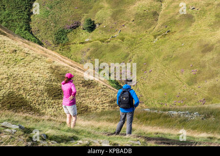 Les randonneurs sur l'échelle de Jacob de prendre dans la vue panoramique sur la vallée et la colline raide en face de Kinder Scout, Derbyshire, Angleterre, RU Banque D'Images