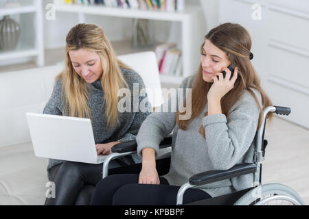 Utilisateur de fauteuil roulant sur le téléphone pendant qu'ami utilise coffre Banque D'Images