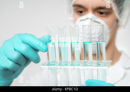 Keen scientist in Protective wear protéine effectue une analyse. Shallow DOF, accent sur les tubes et une main gantée. Banque D'Images