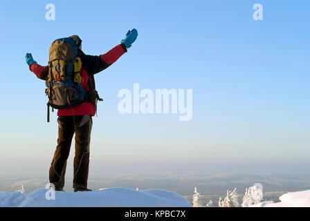Le meilleur homme avec un sac à dos sur le dessus de la montagne d'hiver se propager ses bras, admirant le paysage Banque D'Images