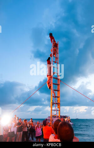 Acrobates sur l'échelle verticale stand effectuer célébration au coucher du soleil de Floride Key West Banque D'Images