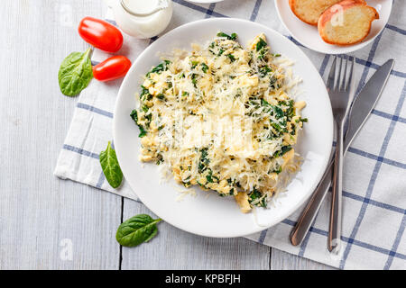 Omelette aux épinards et fromage sur une assiette blanche, café et jus d'orange sur une table en bois blanc. Servir pour le petit déjeuner Banque D'Images