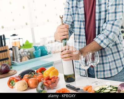 L'homme de l'ouverture d'une bouteille de vin blanc dans la cuisine, il est à l'aide d'un tire-bouchon Banque D'Images