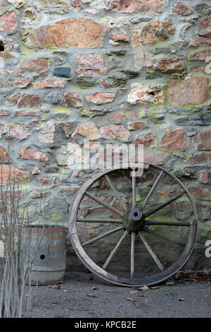 Vieille roue de chariot et le fourreau en bois sur un mur en pierre Banque D'Images