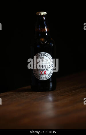 Une bouteille de Guinness Extra Stout original sur une table dans un pub. Banque D'Images