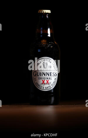 Une bouteille de Guinness Extra Stout original sur une table dans un pub. Banque D'Images