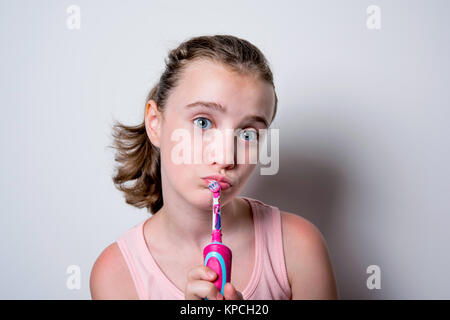 Petite fille heureuse avec une brosse à dents électrique sur un fond blanc Banque D'Images