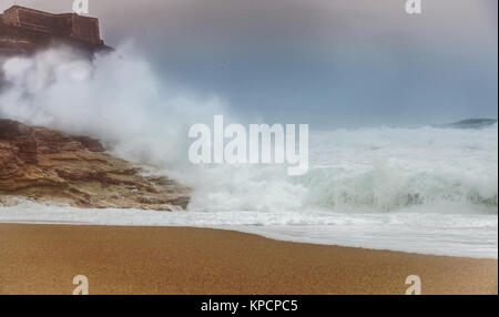 Les ondes de tempête rouler sur la plage et la tape sur les roches Banque D'Images