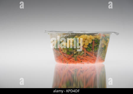 Prêt fait des légumes en pot en plastique prêt à manger sur un fond blanc, pois, maïs sucré et les carottes. Banque D'Images