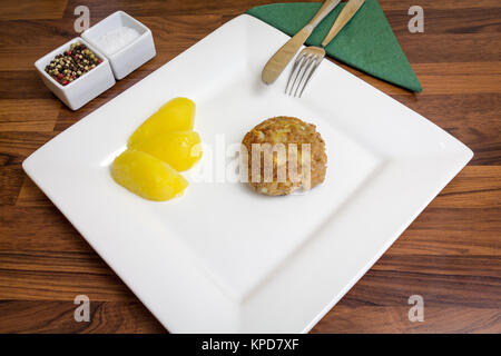 Un frikadeller frites fraîchement sur une plaque blanche,avec des pommes de terre et couverts Banque D'Images