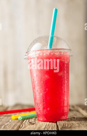 Close Up Still Life Vue de profil de rouge congelé rafraîchissante Slush boisson servi sur table en bois rustique avec des pailles Banque D'Images