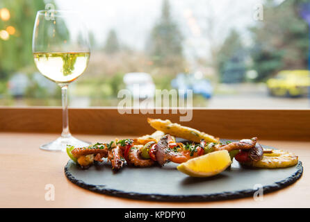 Assortiment de délicieux fruits de mer avec crevettes et poulpe servi sur ardoise avec plaque de verre de vin blanc. Banque D'Images