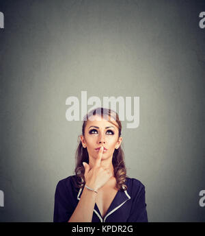 Jeune femme pensive de réflexion sur de nouvelles idées de toucher les lèvres et regardant vers le haut. Banque D'Images