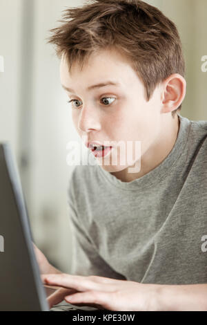 Boy working on Laptop avec visage étonné Banque D'Images