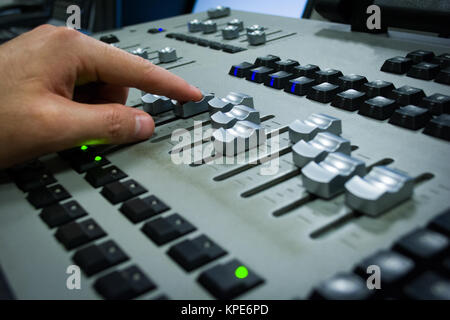 Main sur une table de mixage, lumière dans la télévision fader flou galerie Banque D'Images