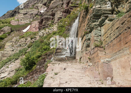 Un randonneur passe par une chute sur le Grinnell Glacier dans le Glacier National Park, Montana Banque D'Images