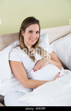 Pregnant Woman Sitting in Bed Banque D'Images