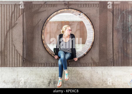 Jeune femme assise urbaine dans city park. Banque D'Images