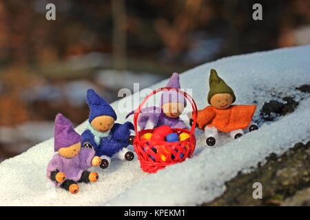 Quatre petits nains avec des œufs de Pâques assis dans la neige Banque D'Images