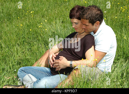 Junge, werdende Eltern sitzen in der Wiese - futurs parents dans le pré Banque D'Images