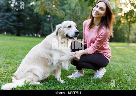 Image de la femme avec chien patte donnant sur pelouse au parc d'été Banque D'Images