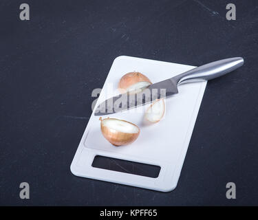 Couteau de cuisine en acier inoxydable et couper l'oignon sur une planche à découper. Banque D'Images