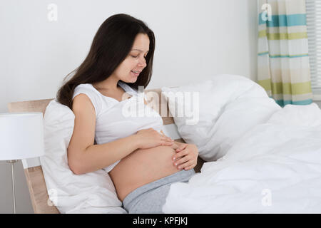 Expecting Woman Sitting on Bed Banque D'Images