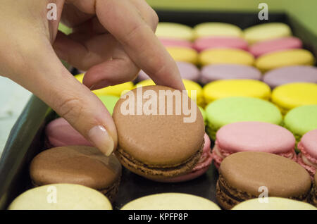 La prise de main de femme colorés savoureux macarons de fort Banque D'Images
