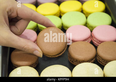 La prise de main de femme colorés savoureux macarons de fort Banque D'Images