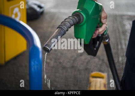 La pompe à gaz mâle main tenant une dernière goutte de carburant fossile Banque D'Images