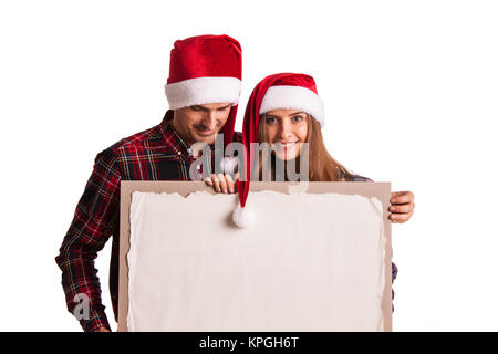 Couple heureux dans Santa hats holding blank banner with copy space Banque D'Images