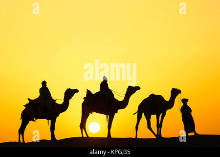 Les chameaux et chamelier silhouetté au coucher du soleil / désert du Thar, Jodhpur, Inde Banque D'Images