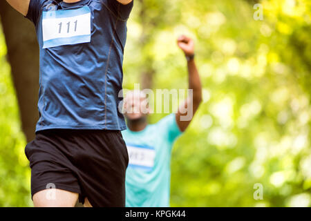 Méconnaissable jeunes coureurs franchir la ligne d'arrivée. Banque D'Images