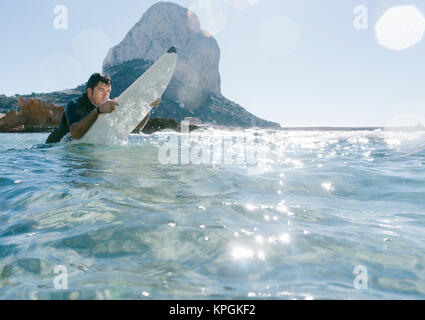 L'homme nage avec sa planche de surf en essayant d'attraper une vague dans la mer méditerranée. Banque D'Images